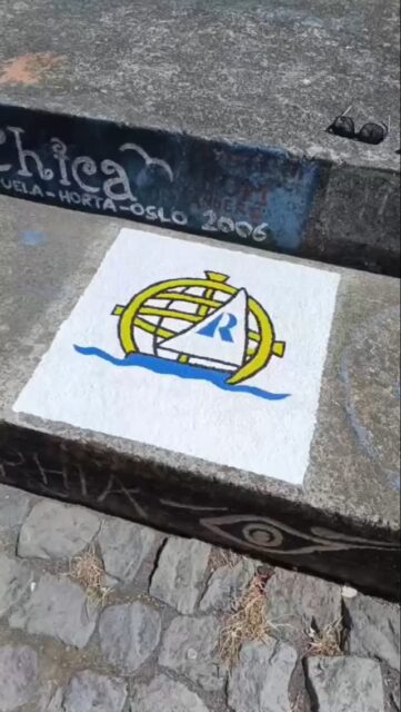 Here, on the harbour wall of Horta, we add our colours to a story written in salt and wind.
For decades, sailors from every horizon have left their mark here—small painted fragments of journeys that crossed the wide Atlantic, each one a promise kept between sea and crew.

Our hands follow the same ritual: brush on stone, pigment meeting sunlight, an image that will remain long after our sails have gone. This is not just a sign—it is a handshake with every sailor who came before, and a beacon for those yet to arrive.

In this island, where the ocean always whispers of faraway places, our mark says: we were here, we faced the sea, and we made it.
And now, our story joins the great mural of the mariners.

#HortaHarbour #SailorsTradition #AtlanticCrossing #WeWereHere #LisbonToHorta #SailingLife #LeaveYourMark